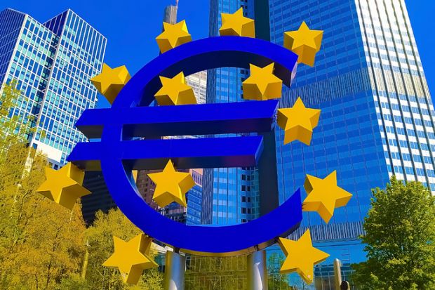 Frankfurt, Germany - April 24, 2022 Euro sign sculpture in a park among modern office towers in Frankfurt