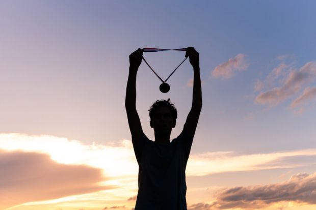 An athlete holds up their medal, illustratiung TEF ratings