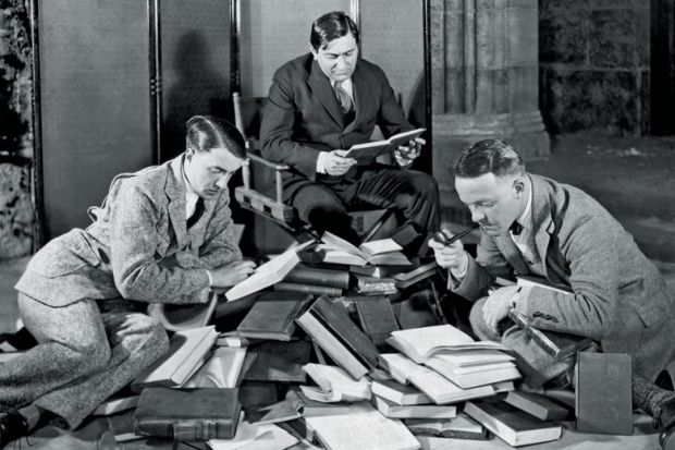 Group of men reading pile of books Group of men reading pile of books