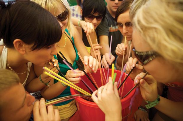 Group of women drinking through straws from bucket Group of women drinking through straws from bucket