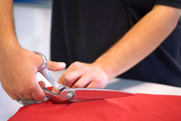 Hand cutting red cloth with scissors Hand cutting red cloth with scissors