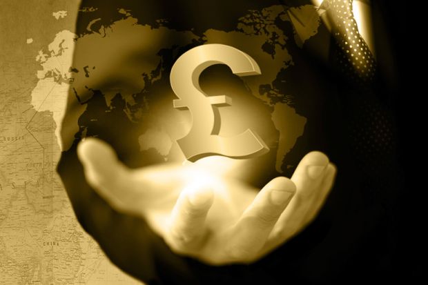 Hand holding UK pound currency symbol against world map