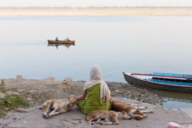 Indian woman meditating Scarfed young indian woman meditating on the border of the Ganges
