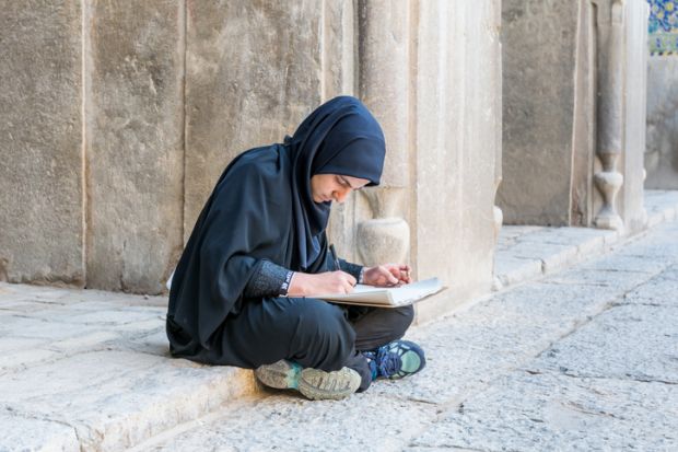 An Iranian student sits on the ground, illustrating inequliaty in university entrance