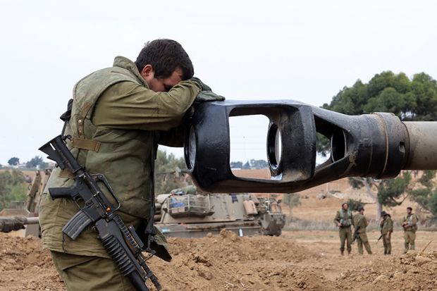 An Israeli soldier rests his head on the gun barrel of a self-propelled artillery howitzer as Israeli soldiers take positions near the border with Gaza in southern Israel on October 9, 2023 An Israeli soldier rests his head on the gun barrel of a self-propelled artillery howitzer as Israeli soldiers take positions near the border with Gaza in southern Israel on October 9, 2023
