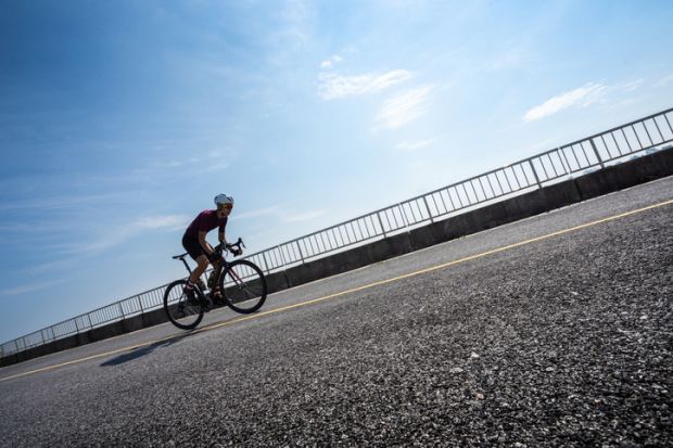 Cyclist cycling uphill on road