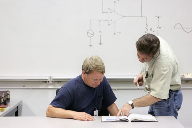 Mature student being shown text by teacher