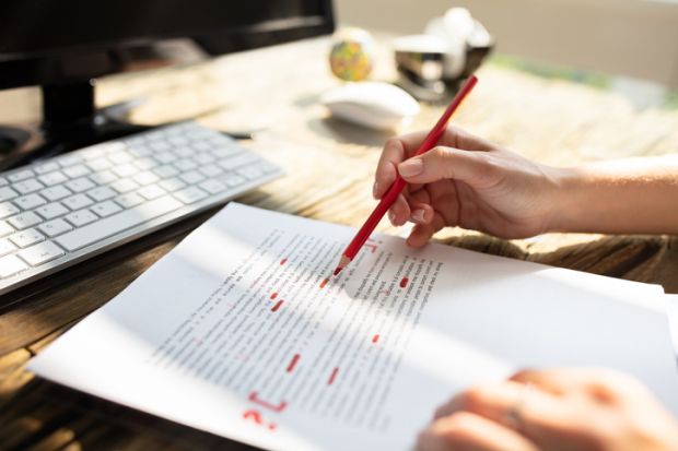 Person marking an error on a page with red marker Person marking an error on a page with red marker