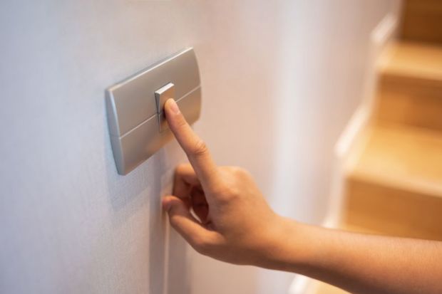 Closeup of finger is turning on or off on light switch at the house