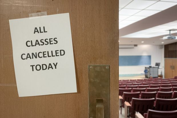 Close-Up of a Notice on a Door to an Empty Classroom that Reads "All Classes Cancelled Today"