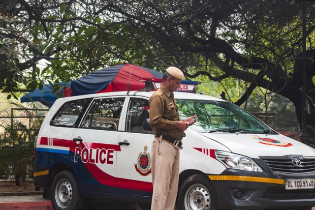 Delhi, India: A policeman in front of a red and white mini van patrolling the state border of the Delhi, state. Delhi, India: A policeman in front of a red and white mini van patrolling the state border of the Delhi, state.