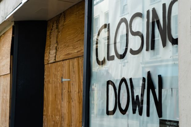 Closing down sign in a boarded-up shop window