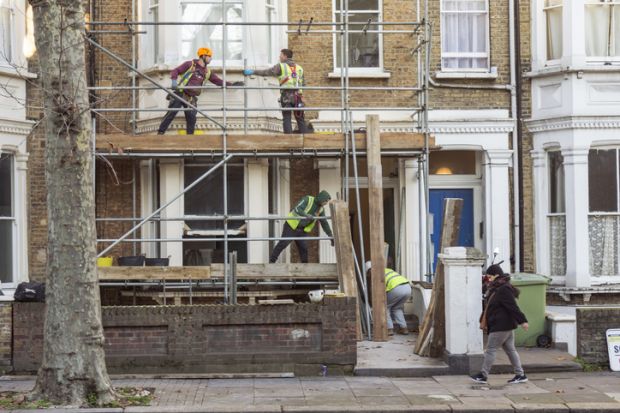 Four workers collaborate to build a scaffold during the refurbishment of a residential premises in London. Four workers collaborate to build a scaffold during the refurbishment of a residential premises in London.