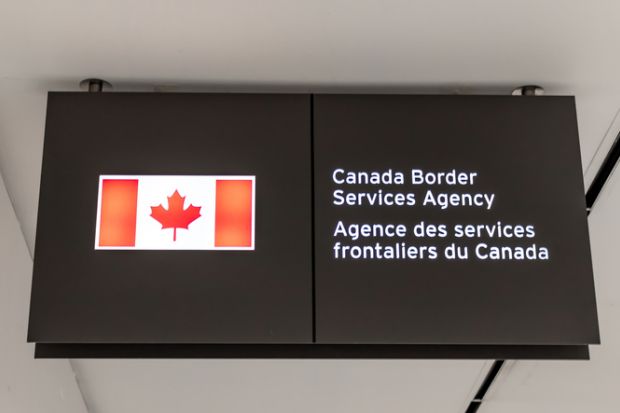 A Canadian flag next to a bilingual sign reading Canada Border Services Agency located in Terminal 3 of Toronto Pearson airport