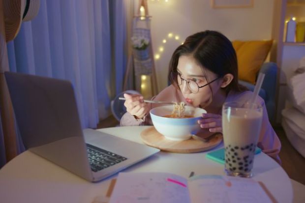 Asian woman eating ramen alone