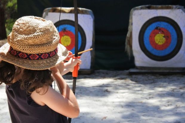 Young girl archer aiming to target.