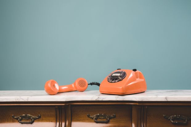 View of an old retro telephone with the receiver off the hook on a table View of an old retro telephone with the receiver off the hook on a table