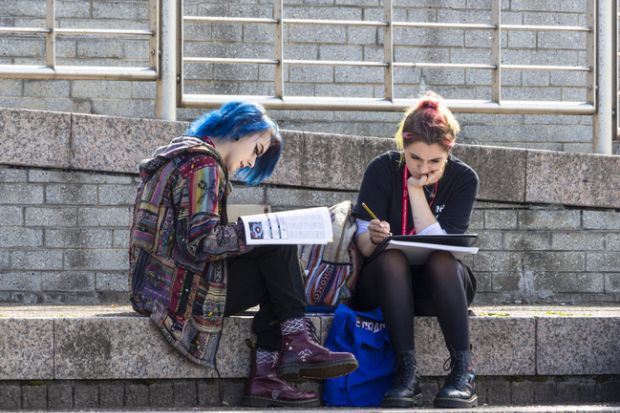Two young female students studying outdoors. Two young female students studying outdoors.