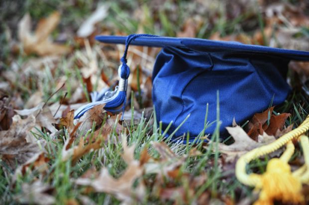 Graduation cap on ground among leaves