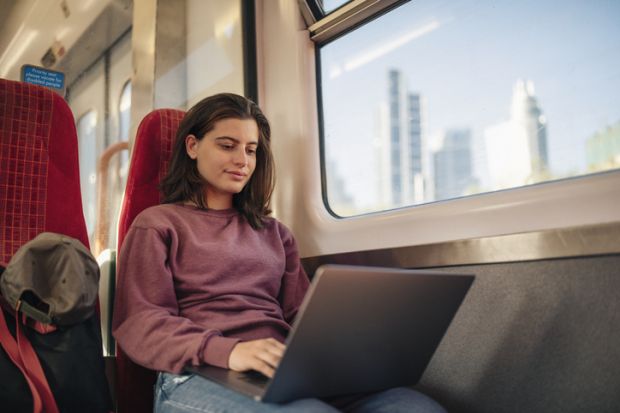 Student commuter on laptop on train Student commuter on laptop on train
