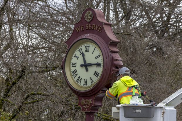 A close up of a city of Vancouver worker fixing an outdoor public clock at the Queen Elizabeth Park in Vancouver, British Columbia. A close up of a city of Vancouver worker fixing an outdoor public clock at the Queen Elizabeth Park in Vancouver, British Columbia.