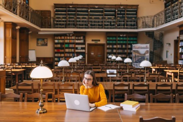Student studying on laptop in library
