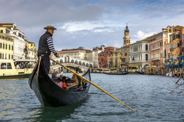 View of the beautiful Rialto Bridge spanning the Grand Canal with gondolier in foreground in Venice, Italy View of the beautiful Rialto Bridge spanning the Grand Canal with gondolier in foreground in Venice, Italy