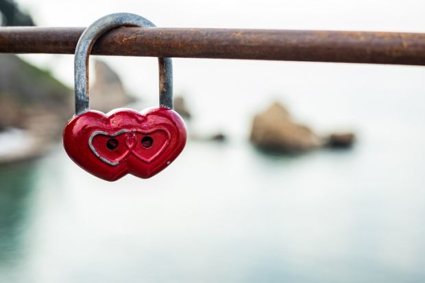 Red double heart padlock hangs on bridge