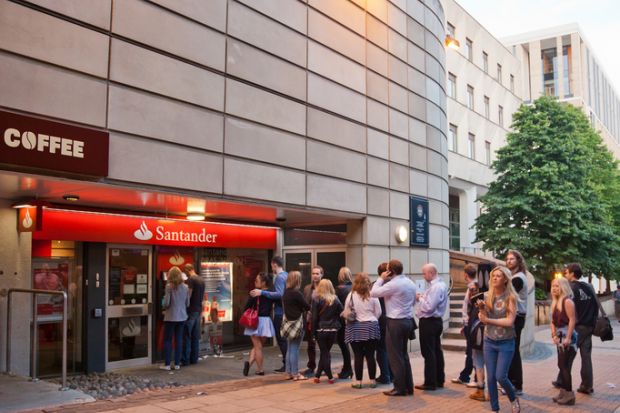 Queue of people waiting at a Santander ATM; central Edinburgh.
