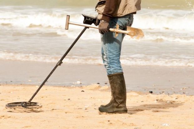 Person on beach using metal detector