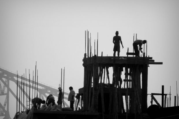 Construction workers and Engineers working for the construction of a high rise building in Kolkata with the famous Howrah Bridge in the background.