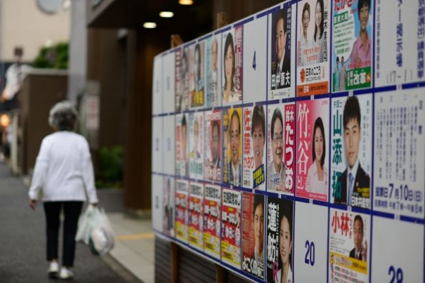 Woman walks past election posters