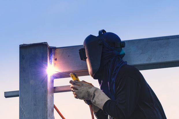 Worker welding parts of steel construction together