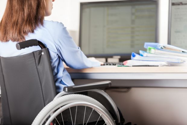 A wheelchair users works at a computer A wheelchair users works at a computer