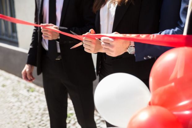 Close-up Of Businesspeople Hand Cutting Red Ribbon With Scissors Close-up Of Businesspeople Hand Cutting Red Ribbon With Scissors
