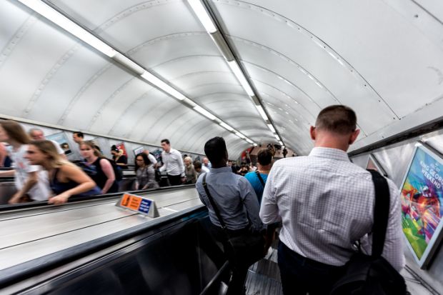 Men riding escalator walking down standing in underground tube