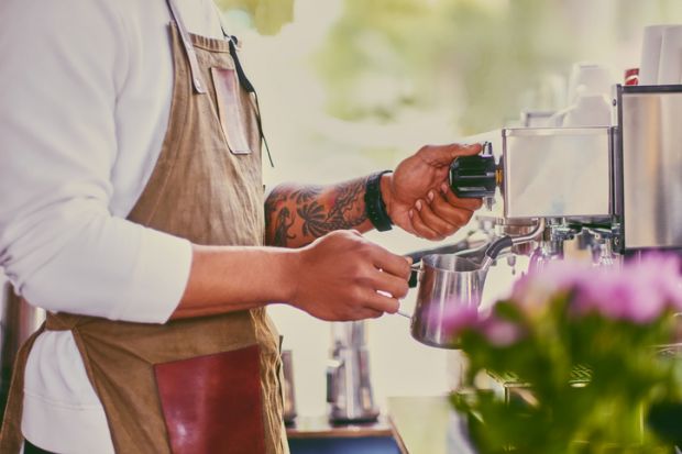 Close up image of a man preparing late in a coffee machine.