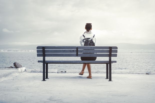 Woman sits alone on a bench Woman sits alone on a bench illustrating the isolating experience of transitioning from academia into industry