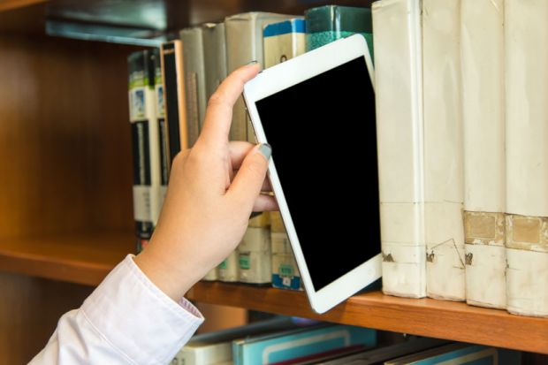 Hand placing a tablet on a library bookshelf