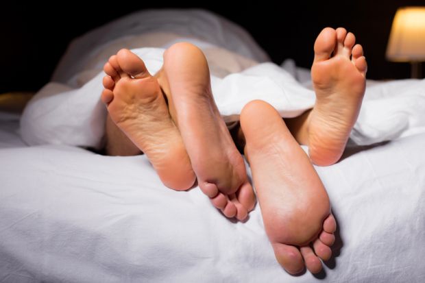 Feet emerging from a bed