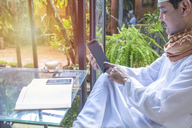 A Pakistani man works on a phone in a coffee shop
