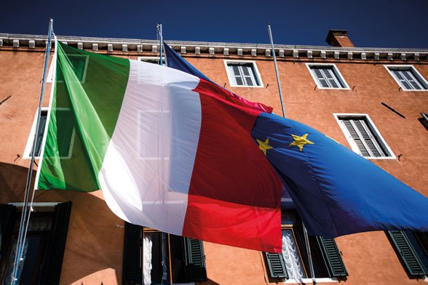 Italian flag flying in front of European Union flag, to suggest how Italy’s discrimination against foreign lecturers defies European law and justice Italian flag flying in front of European Union flag, to suggest how Italy’s discrimination against foreign lecturers defies European law and justice