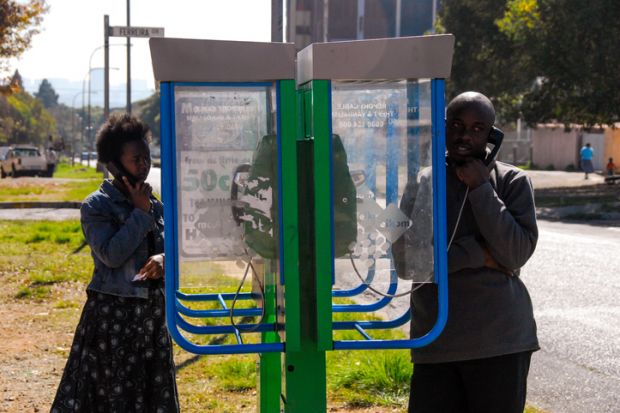 Johannesburg , Gauteng  South Africa -august 31 2012  man and woman talking on a sidewalk pay phone midday Rosettenville Johannesburg