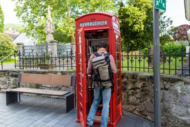 In Germany, a red telephone booth is used for the free exchange of books – a man is looking inside