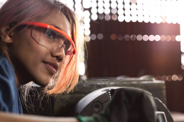 An Asian woman works heavy machinery