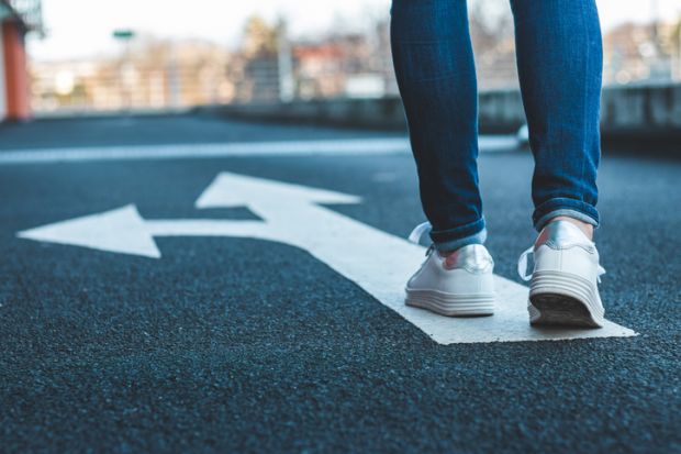 Make decision which way to go, walking on directional sign on asphalt road