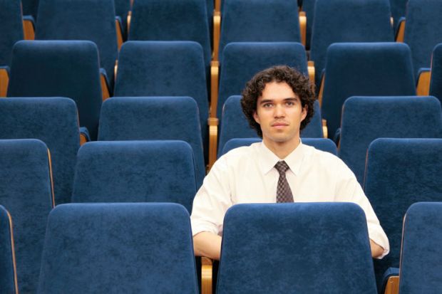 Male student sitting alone in lecture hall Male student sitting alone in lecture hall