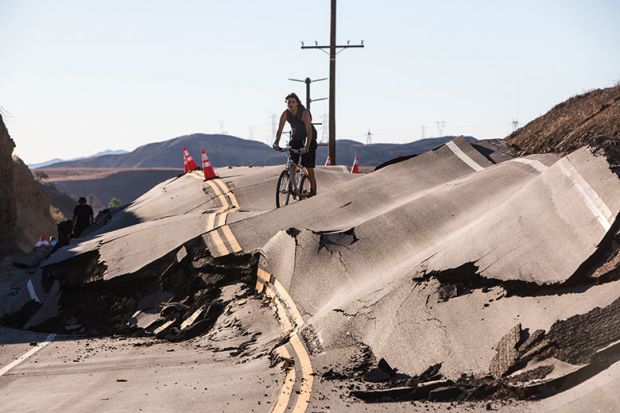 Man cycles along severely damaged road Man cycles along severely damaged road
