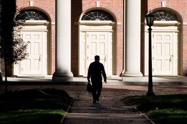 A man hidden in shadows walking towards entrance of building. To illustrate that staff accused of sexual harassment are free to leave their position and gain a new job at a different institution with no obligation to disclose any allegations.