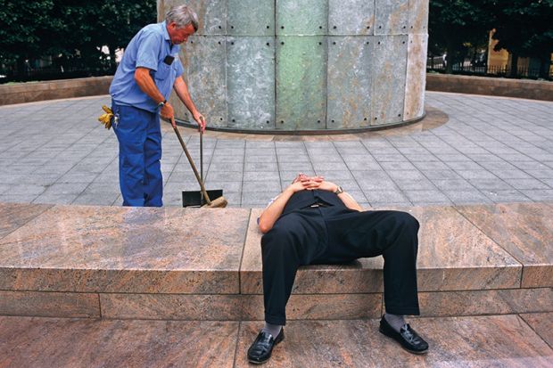 Man lays down while another works behind